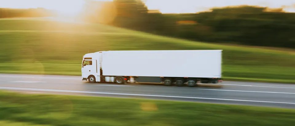 Unmarked white lorry on a motorway at sunset